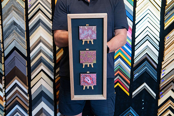 Three miniature artworks on timber easels displayed in a custom natural timber shadow box frame by Sunset Framing & Gallery Port Macquarie.