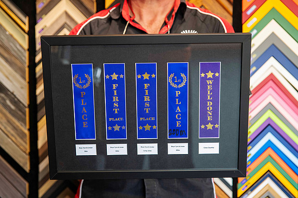 Boys athletics and cross-country award ribbons including first place ribbons, individually mounted and professionally custom framed in Port Macquarie.