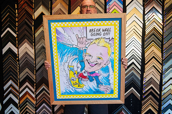 Colourful Australian surfing cartoon artwork featuring a surfer and Break Wall Going Off text, custom framed in a wide natural timber frame in Port Macquarie.