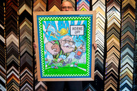 Colourful Australian rugby cartoon artwork featuring a football player and Horns Up text, custom framed in a wide natural timber frame in Port Macquarie.