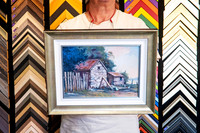 Rustic Australian country landscape painting featuring stone sheds and timber fencing, professionally custom framed with white inner and antique-style outer framing in Port Macquarie.