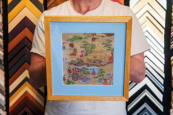 Detailed Asian embroidered textile artwork professionally custom framed with soft blue matboard and a natural timber picture frame in Port Macquarie.