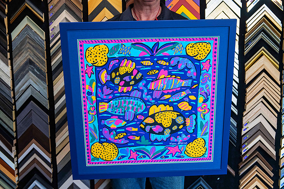 Colourful Ken Done fish design scarf professionally custom framed as textile wall art with a deep blue background and blue picture frame in Port Macquarie.