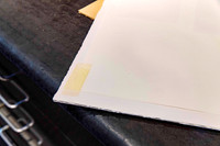 Artwork dropped inside a picture frame after masking tape used by a previous framer failed, shown during professional frame repair at Sunset Framing & Gallery Port Macquarie.