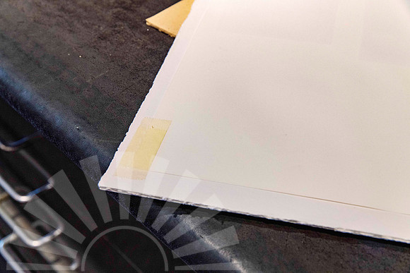 Artwork dropped inside a picture frame after masking tape used by a previous framer failed, shown during professional frame repair at Sunset Framing & Gallery Port Macquarie.