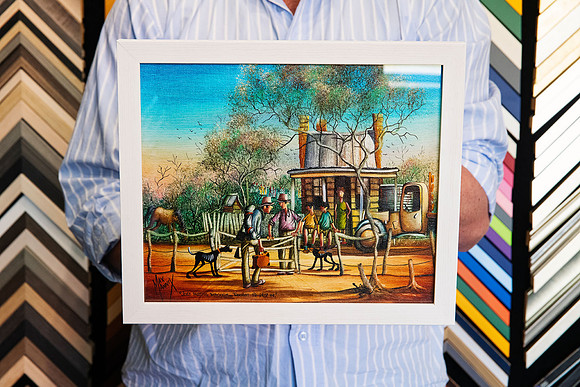 Colourful original Australian artwork depicting an outback scene with people, dogs and a country homestead, custom framed in a simple white frame behind glass in Port Macquarie.