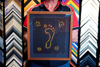 Hand-painted dot artwork with central footprint float mounted on a dark mat and custom framed in warm timber by Sunset Framing & Gallery Port Macquarie.