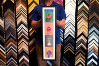 Four colourful travel prints arranged vertically in a long narrow black custom frame with white surround.