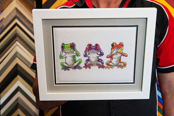 Colourful three frogs cross stitch framed with layered grey and black matting and a white custom frame in Port Macquarie.