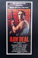 Raw Deal Australian Daybill showing Arnold Schwarzenegger in a grey singlet holding a firearm, against repeated red-orange surname lettering and a large red title.