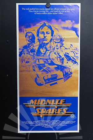 Midnite Spares Australian Daybill with blue illustrated character portraits, a modified tow truck and an airborne car on orange, above an automotive-style title.