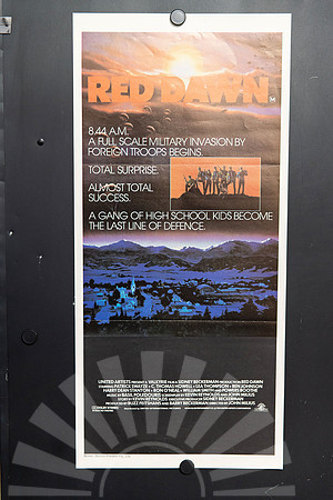 Red Dawn Australian Daybill with an orange title, parachutes descending through a dawn sky, an inset of armed young fighters and a blue-toned town beneath mountains.