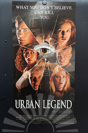 Urban Legend Australian Daybill featuring six cast portraits and newspaper clippings arranged in shattered-glass fragments around a yellow eye, with a large white title on black.