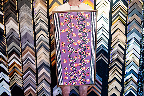 Purple Aboriginal artwork with detailed dot painting framed in a narrow timber frame.