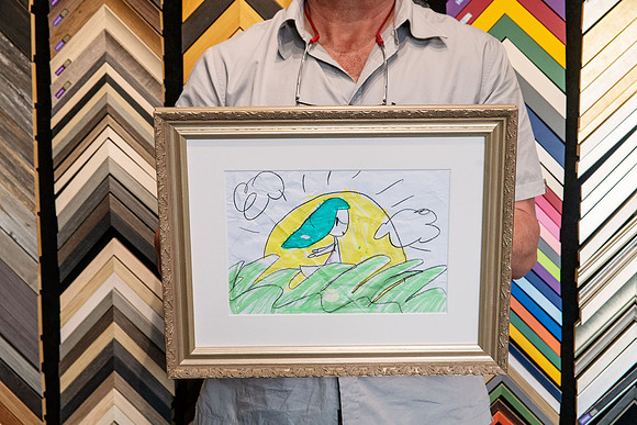 Colourful child's drawing professionally custom framed with mat and decorative frame.