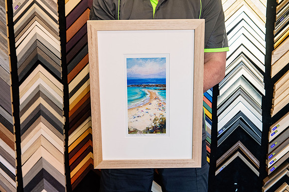 Small coastal artwork framed with wide white mat and natural timber frame.