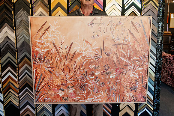 Large botanical artwork in earthy tones custom framed with a slim natural timber picture frame.
