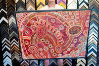 Large Aboriginal artwork in orange, red and pink tones finished with a slim dark frame.