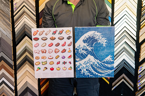 Two printed canvases showing pixel art and wave artwork professionally stretched for display.