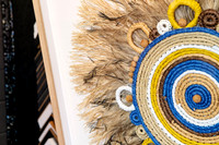 Close-up of woven fibre and feather artwork professionally mounted within a custom timber picture frame.