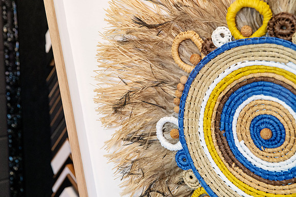 Close-up of woven fibre and feather artwork professionally mounted within a custom timber picture frame.